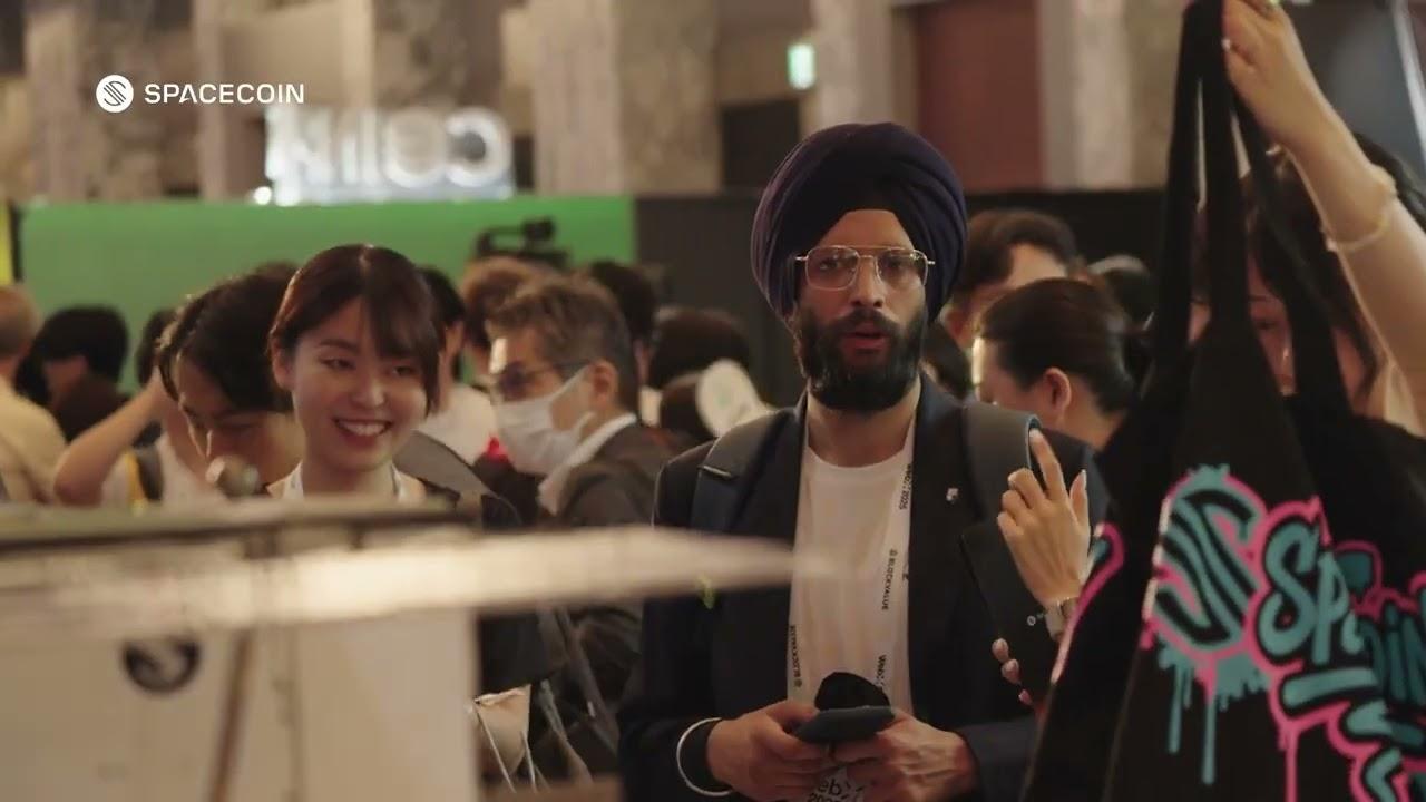 Attendees crowding the SpaceCoin booth at WebX 2025 in Tokyo, one holding up a SpaceCoin tote bag